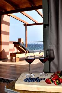 two glasses of red wine on a cutting board with fruit at Αιγιαλίς - Πολυτελη διαμερισματα in Karistos