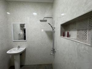 y baño blanco con lavabo y ducha. en Complexe La Perfection en Nuakchot