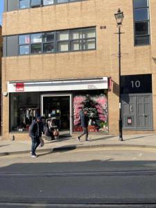 two people walking down a street in front of a store at Inviting Studio Apartment - Central Croydon London in London
