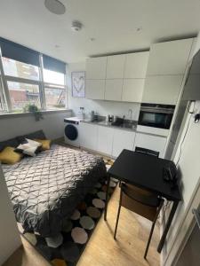 a bedroom with a bed and a table and a kitchen at Inviting Studio Apartment - Central Croydon London in London