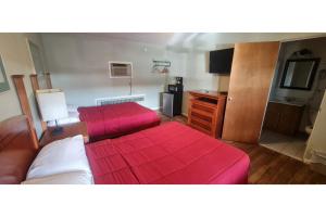 a bedroom with two beds with red sheets at Werry's Cottages Motel & Pub by OYO East Stroudsburg Poconos in East Stroudsburg