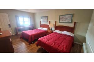 two beds in a hotel room with red sheets at Werry's Cottages Motel & Pub by OYO East Stroudsburg Poconos in East Stroudsburg