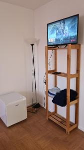 einen TV auf einem Holzständer in einem Zimmer in der Unterkunft Chambre Privée chez l'habitant in Bourg-la-Reine