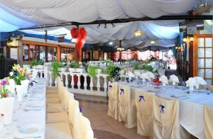 um grupo de mesas com toalhas de mesa brancas e flores em Hotel Garden em Nuraminis
