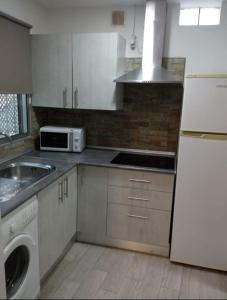 a kitchen with white cabinets and a sink and a microwave at Estudio en Jerez in Jerez de la Frontera