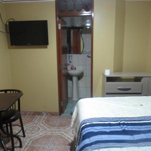 a bedroom with a bed and a bathroom with a sink at Gran Hostal Los Pinos in Cajamarca