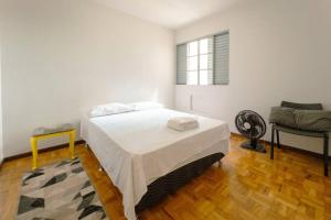 a white room with a bed and a chair at Espaçoso e Confortável Próximo da UEM - EL08 in Maringá