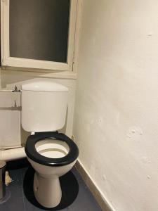 uma casa de banho com um WC branco com um assento preto em Welcome em Chambéry