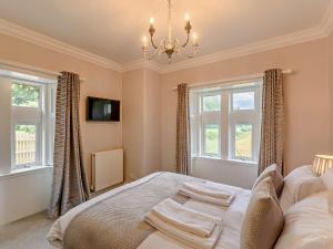 a bedroom with a bed with a chandelier and windows at 2 Bed in Hawick 91905 in Roberton