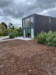 a black house with glass doors on a yard at Luxe lodges met airco in Oostkapelle