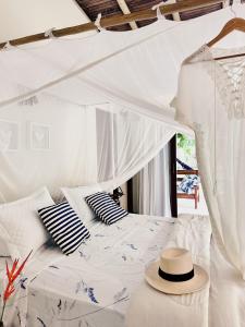 um quarto com uma cama branca com um chapéu em Refugio Trancoso suite Mare em Trancoso