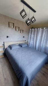 een groot bed in een slaapkamer met blauwe lakens bij Le Panoramique, Calme - Spacieux in Chateauroux-les-Alpes