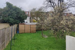 a backyard with a wooden fence and a yard with trees at Large Studio Garden Flat on Golders Green Road in London