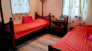 a bedroom with two beds with red sheets at The Patnem villa in Canacona