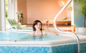 a woman in a swimming pool eating a slice of watermelon at Ferienhäuser Hoher Knochen in Winterberg