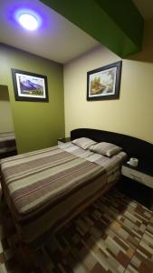 a bedroom with a bed and two pictures on the wall at Hostal Nochero's in Tacna