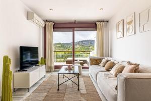 een woonkamer met een bank en een tv bij RentitSpain Charming Apartment in Parque Botanico Resort & Country Club, Marbella, Estepona, Benahavis in Estepona