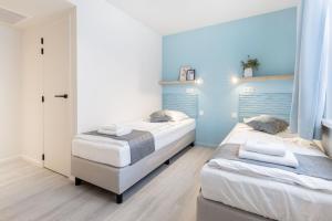 2 łóżka w pokoju z niebieskimi ścianami w obiekcie Hotel José w mieście Blankenberge