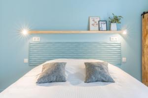 een bed met 2 kussens in een blauwe slaapkamer bij Hotel José in Blankenberge