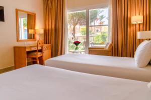 a hotel room with two beds and a desk and a window at Sierra Sharm El Sheikh in Sharm El Sheikh