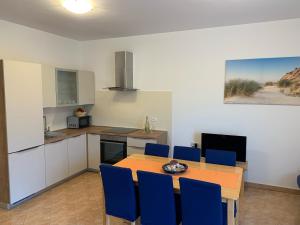 cocina con mesa de madera y sillas azules en Apartment Greta en Kanfanar