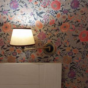 a lamp on top of a dresser with a floral wallpaper at Hotel Montreal in Florence