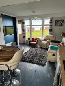 a living room with a table and a couch at Cosy Beach Chalet in Scratby