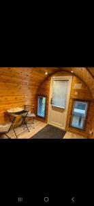 a room with a table and two windows and a wooden wall at New hotub glamping pods in Kinlet
