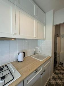 cocina con armarios blancos, fregadero y encimera en Luxury Studio near University Square, en Bucarest