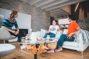 a group of three women sitting in a living room at Ferienhäuser Hoher Knochen mit Sauna in Schmallenberg +29 photos