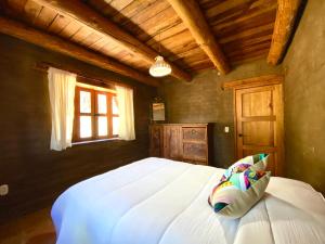1 dormitorio con 1 cama blanca grande y techo de madera en Aldea punta de agua, en Sayula