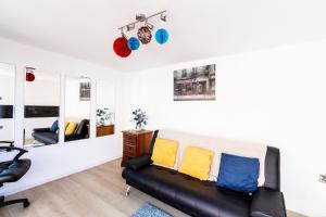 una sala de estar con un sofá de cuero negro y espejos en Spacious 3BR House with Garden & Free Parking, en Mánchester