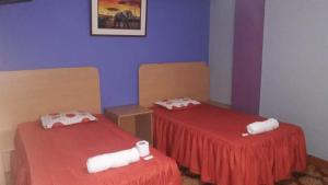 two beds in a room with red sheets at Hostal Nochero's in Tacna