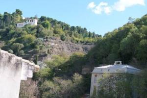 a building on the side of a hill with trees at Apartamento Casa Ruan Albaicín, Torre de Comarex in Granada