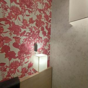 a bathroom with a red flower patterned wall at Hotel Montreal in Florence
