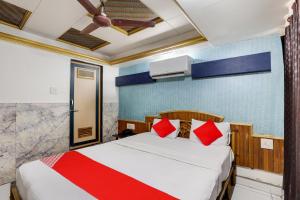 a bedroom with a bed with red pillows at OYO Flagship Hotel Ravi Palace in Rajkot