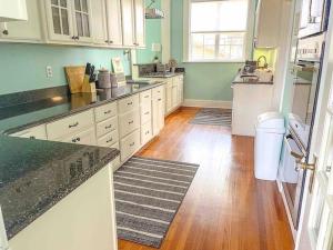 a kitchen with white cabinets and a wooden floor at Timeless Charm: Discover the 1918 CE Smith House! in Little Rock