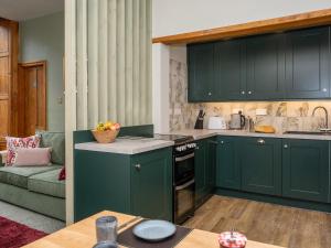Una cocina con gabinetes verdes y un sofá. en Watermouth Castle, Bassett Apartment, en Ilfracombe