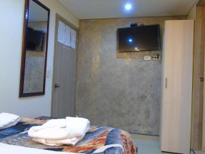 a bedroom with a bed with a tv on the wall at Hotel Restaurante El Madroño Chia in Chía