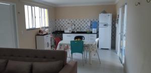 a kitchen with a table and a white refrigerator at Casa Super em São Miguel do Gostoso RN in São Miguel do Gostoso