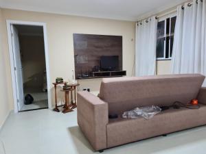 a living room with a brown couch and a television at Casa Super em São Miguel do Gostoso RN in São Miguel do Gostoso