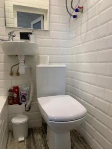a white bathroom with a toilet and a sink at Luxury_loft in Kamianets-Podilskyi
