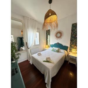 Un dormitorio con una gran cama blanca y una lámpara de araña. en La Nueva Casa del Barco del Humo, en Vigo