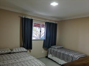 a bedroom with two beds and a window at Casa Super em São Miguel do Gostoso RN in São Miguel do Gostoso