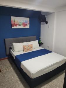 Costana - Hostal في كارتاهينا دي اندياس: غرفة نوم بسرير كبير بجدار ازرق