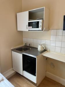 a small kitchen with a sink and a microwave at Anwar House in London