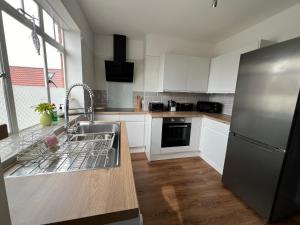 a kitchen with white cabinets and a stainless steel refrigerator at Glastonbury Town Centre - Large 2 Bedroom Apt With Balcony in Glastonbury