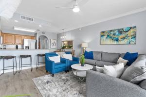 a living room with a couch and a kitchen at Scenic View Condo Near Disney in Orlando