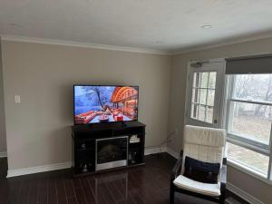 a living room with a flat screen tv and a chair at Enjoy luxury living in Mississauga