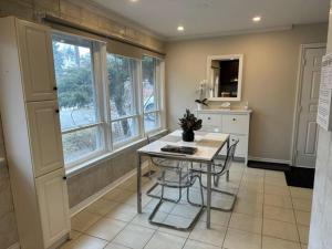 uma cozinha com uma mesa, 2 cadeiras e janelas em Enjoy luxury living em Mississauga